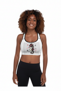 Woman with curly hair wearing white padded racerback sports bra with black trim and colorful seahorse floral graphic, paired with black leggings